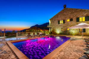 a house with a swimming pool with purple lights at Luxury villa with a swimming pool Dubravka, Dubrovnik - 11073 in Gruda