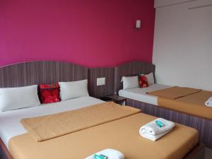 two beds in a room with pink walls at Malhar palace hotel in Shirdi