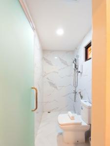 a bathroom with a toilet and a white wall at Hotel Simone Kalibo in Kalibo