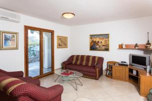 a living room with a couch and a tv at Family friendly apartments with a swimming pool Trstenik, Peljesac - 11081 in Trstenik