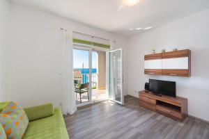 sala de estar con sofá verde y TV en Apartments by the sea Brist, Makarska - 11078 en Brist
