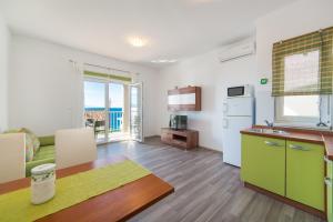 cocina y sala de estar con mesa y nevera en Apartments by the sea Brist, Makarska - 11078 en Brist