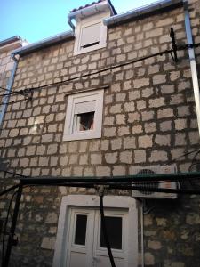 um edifício de tijolos com uma janela e uma pessoa nele em Seaside holiday house Kastel Stafilic, Kastela - 11165 em Kaštela