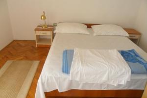 um quarto com uma cama com lençóis brancos e uma mesa em Apartments by the sea Kozino, Zadar - 11169 em Petrcane