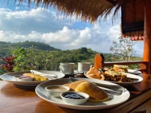 een tafel met borden met voedsel erop met uitzicht bij Alit Cottage in Nusa Penida