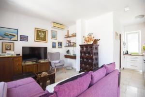 a living room with a purple couch and a tv at Apartments by the sea Splitska, Brac - 11300 in Splitska