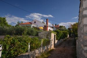 a stone wall with bushes and houses in the background at Apartments by the sea Splitska, Brac - 11339 in Splitska