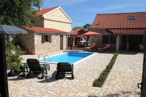 um quintal com piscina e cadeiras e uma casa em Family friendly house with a swimming pool Gluici, Krka - 11337 em Validžići