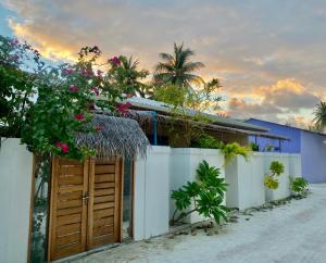 een huis aan het strand met een hek en bloemen bij Sands Inn, Mathiveri in Mathiveri