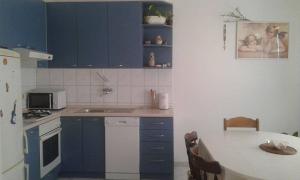 a kitchen with blue cabinets and a table and a table and a tableablish at Apartments with a parking space Stanici, Omis - 11376 in Čelina