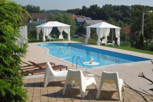 a pool with white chairs and a table and umbrellas at Apartments with a swimming pool Zagreb - 11408 in Zagreb