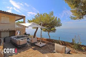 un patio con sofá, sombrilla y el océano en A couper le souffle Magnifique Villa sur l'eau, en La Redonne