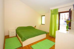 een slaapkamer met een groen bed en groene gordijnen bij Apartments with a parking space Makarska - 11418 in Makarska