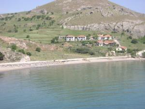 a house on a hill next to a body of water at Sunset Hotel in Agios Ioannis Kaspaka