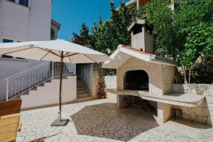 un patio con sombrilla y horno de pizza en Apartments with a parking space Mastrinka, Ciovo - 11283 en Trogir