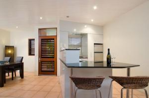 a kitchen and dining room with a counter and chairs at L'Auberge @ Noosa in Noosa Heads