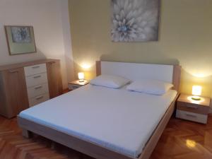 a bedroom with a large white bed with two lamps at Apartments by the sea Arbanija, Ciovo - 11321 in Trogir