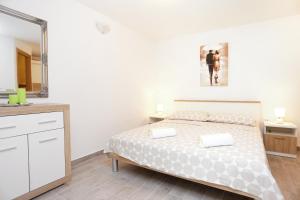 Habitación blanca con cama y espejo en Apartments by the sea Kastel Kambelovac, Kastela - 8679, en Kaštela