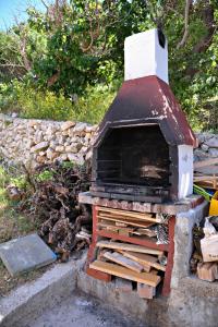 a wood fired oven sitting next to a stone wall at Apartments by the sea Metajna, Pag - 10405 in Zubovići