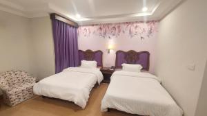 um quarto com duas camas e uma cadeira em Hotel One Sargodha em Sargodha