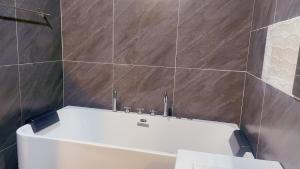 a white bath tub in a bathroom with brown tiles at 3 Bedroom Villa Praitumnak soi 4 by Daisy Pattaya in Pattaya South