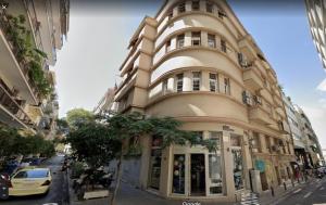 un edificio alto en una calle de la ciudad con un coche aparcado delante en Neo Luxury Suite en Athens