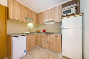 a kitchen with wooden cabinets and a white refrigerator at Apartments with a parking space Nin, Zadar - 10414 in Nin