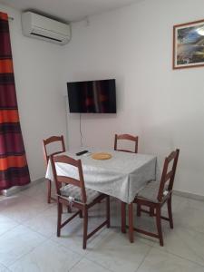 a table with four chairs and a television on a wall at Apartments by the sea Cove Blaca, Mljet - 10416 in Maranovići