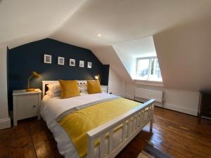a bedroom with a large bed with a yellow blanket at Charming Cottage mins from Chichester City Centre in Chichester