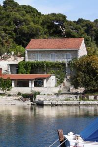 ein Haus auf dem Wasser mit einem Boot davor in der Unterkunft Apartments by the sea Pomena, Mljet - 10426 in Goveđari