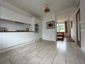 a kitchen with white cabinets and a tile floor at Gower Getaway - Parking & Ensuite in Swansea