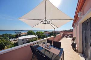 a balcony with a table and a white umbrella at Apartments by the sea Tkon, Pasman - 8414 in Tkon