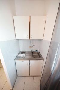 a small kitchen with a sink and white cabinets at Apartments by the sea Tkon, Pasman - 8414 in Tkon