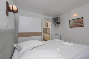 ein weißes Bett in einem weißen Schlafzimmer mit einem TV in der Unterkunft Studio Pokrivenik 10427a in Zastražišće