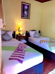 Pokój z 2 łóżkami i stołem z lampką w obiekcie BKC villa w mieście Pakbeng