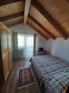 a bedroom with a bed and a large window at Casuta Pietrosul Rodnei in Borşa