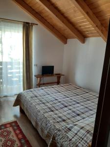 1 dormitorio con cama y mesa con ordenador portátil en Casuta Pietrosul Rodnei, en Borşa