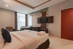 a hotel room with a large bed and a desk at Urbanview Hotel Newton Riau Bandung by RedDoorz in Bandung