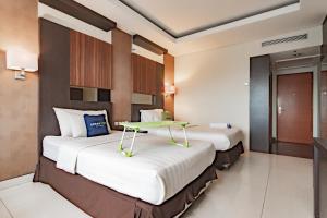 two beds in a hotel room with a table on it at Urbanview Hotel Newton Riau Bandung by RedDoorz in Bandung +50 photos