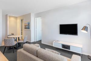 a living room with a couch and a tv and a table at Meriton Suites Campbell Street, Sydney in Sydney