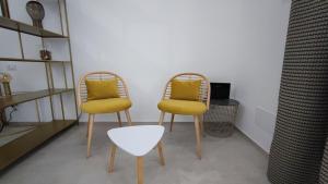 two chairs with yellow cushions sitting in a room at Dimore Gilas - Suite Golden in Monopoli