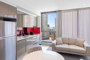 a kitchen with a couch and a table at Meriton Suites Campbell Street, Sydney in Sydney