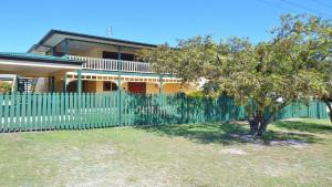 a fence in front of a house with a tree at Amberlee House - bring your own linen in South West Rocks