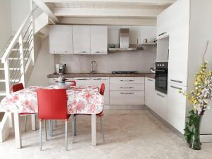 a kitchen with white cabinets and a table with red chairs at Dimora dAmare in Trani