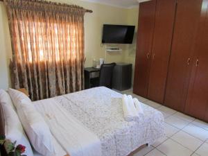 um quarto de hotel com uma cama e uma televisão em Lalamnandzi2 em White River