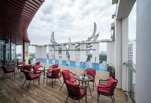 eine Dachterrasse mit Tischen und Stühlen auf einem Gebäude in der Unterkunft Muong Thanh Luxury Saigon Hotel in Ho-Chi-Minh-Stadt