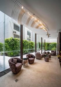 a living room with couches and chairs and windows at Muong Thanh Luxury Saigon Hotel in Ho Chi Minh City