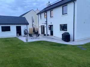 a yard with a house and a patio with a table and chairs at Beautiful private room and bathroom in Ballycastle