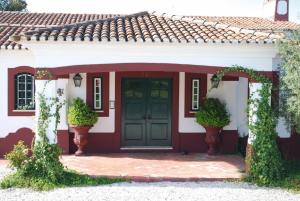 una casa roja y blanca con una puerta verde en Moinho Do Álamo en Montemor-o-Novo