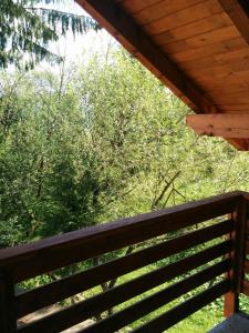 a wooden bench under a roof with trees in the background at Casuta Pietrosul Rodnei in Borşa
